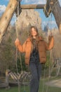 Portrait of a teenage girl standing on a swing and listening to music on a mountain background.