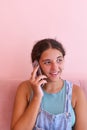 Portrait of a teenage girl talking on the phone, pink background, vertical image Royalty Free Stock Photo