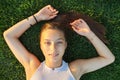 Portrait of a teenage girl, top view, smiling beautiful female lying on green grass Royalty Free Stock Photo