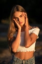 Portrait of teenage girl touching her face with her palms. Young Caucasian lady posing on sunset in nature. Skin care