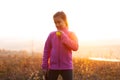 Portrait of teenage girl is training tennis skill outside court, in field at sunset. Wearing pink sweater. Royalty Free Stock Photo