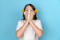 Portrait of a teenage girl with a white scarf who rolls her eyes and sneezes. The concept of seasonal pollen allergy to Royalty Free Stock Photo