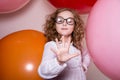 Portrait of a teenage schoolgirl showing five fingers on a background of large rubber balls. Royalty Free Stock Photo