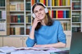 Portrait of teenage student guy sitting at desk in library, looking at camera Royalty Free Stock Photo