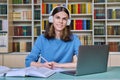 Portrait of teenage student guy sitting at desk in library, looking at camera Royalty Free Stock Photo