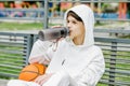 Portrait of teenager boy sitting on bench with basketball and drinking water during break Royalty Free Stock Photo