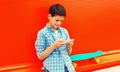 Portrait of teenager boy with smartphone and skateboard on colorful red background Royalty Free Stock Photo