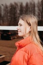 portrait of a teenager girl waking through a city wearing red winter jacket. side view of beautiful teen girl in a town