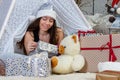 Portrait of a teenager girl wearing a silver color Christmas hat lying between gift boxes Royalty Free Stock Photo