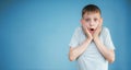 Portrait of a teenager in a gray t-shirt. Photo of a young boy looking at camera on a blue background. He is very surprised, his Royalty Free Stock Photo