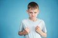 Portrait of a teenager in a gray t-shirt in the studio. Photo of an adorable young boy looking at camera on a blue background. He Royalty Free Stock Photo