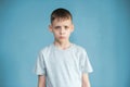 Portrait of a teenager in a gray t-shirt in the studio. Photo of an adorable young boy looking at camera on a blue background. Sad Royalty Free Stock Photo