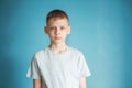 Portrait of a teenager in a gray t-shirt in the studio. Photo of an adorable young boy looking at camera on a blue background. Royalty Free Stock Photo