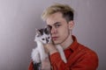 Portrait of a teenager holding a cat on a gray background. Concept: pets, caring for animals, love for our smaller brothers.
