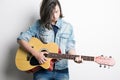 Fashion portrait of a teenager playing guitar in studio wearing jeans jacket Royalty Free Stock Photo