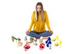 Portrait of a teenager woman sitting on the floor between many pairs of shoes against white. Consumerism concept