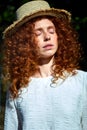 Portrait of tender caucasian redhead female with curly wavy hair posing with eyes closed Royalty Free Stock Photo