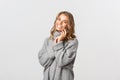 Portrait of tender smiling woman, looking happy and laughing, gently touching face, standing over white background