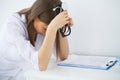 Portrait of tensed doctor sitting at the workplace in the hospital with hand on forehead in hospital