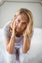 Portrait of tensed woman sitting on bed in bedroom