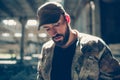 Portrait of terrorist. He is looking down. Guy is standing in a big and empty hangar in a sunny day. Royalty Free Stock Photo