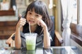 Portrait Thai Asian kid girl, aged 4 to 6 years old, is a cute and beautiful child with long hair. holding a cup of matcha green Royalty Free Stock Photo