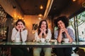 Portrait of thee young women smiling and posing looking at camera on a coffee shop. Photo of a group of happy females on