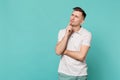 Portrait of thinkful young man in casual clothes looking up, put hand prop up on chin isolated on blue turquoise