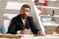 Portrait of thinking male teacher in school classroom. Serious teacher man sitting on desk writing text in book at Royalty Free Stock Photo