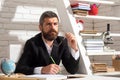 Portrait of thinking male teacher in school classroom. Teacher sitting on desk writing text in book at school classroom. Royalty Free Stock Photo