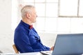 Portrait of thinking senior businessman sitting in the office behind his laptop Royalty Free Stock Photo