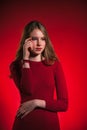 Portrait thinking teen girl closed stylish red dress over red background Royalty Free Stock Photo