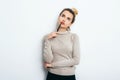 Portrait of Thinking woman with appealing smile, having hair bun in sweater isolated on white background holding pen and have a pe Royalty Free Stock Photo