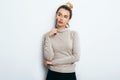 Portrait of Thinking woman with appealing smile, having hair bun in sweater isolated on white background holding pen and have a pe Royalty Free Stock Photo