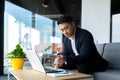 Portrait thoughtful Asian businessman working on a laptop computer at a modern office desk. Confident Focused pensive man Royalty Free Stock Photo