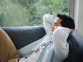 Portrait of thoughtful Asian man on sofa bed feeling lonely looking away and thinking.