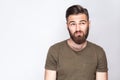 Portrait of thoughtful bearded man with dark green t shirt against light gray background. Royalty Free Stock Photo