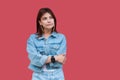 Portrait of thoughtful beautiful brunette young woman with makeup in denim casual style standing with crossed hands and looking Royalty Free Stock Photo