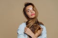 Portrait of thoughtful beautiful woman looks aside, thinks about something pleasant, crosses hair over neck, wears makeup, stylish Royalty Free Stock Photo