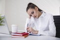 Portrait of a thoughtful brown haired businesswoman in a white blouse sitting at her table in an office. Royalty Free Stock Photo