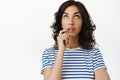 Portrait of thoughtful brunette girl looking up, thinking and making choice, deciding to buy something, pondering while Royalty Free Stock Photo