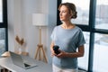 Portrait of thoughtful business woman holding coffee cup and thinking looking away standing on background of large Royalty Free Stock Photo