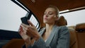 Portrait woman sitting with phone backseat. Female using smartphone at car Royalty Free Stock Photo