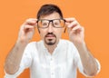 Portrait of thoughtful caucasian man holding eye glasses outstretched and looking through it while standing against Royalty Free Stock Photo