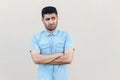 Portrait of thoughtful confused handsome young bearded man in blue shirt standing, crossed arms, looking away and thinking what to Royalty Free Stock Photo