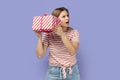 Woman shaking gift box and looking away, trying to guess what inside in present box. Royalty Free Stock Photo