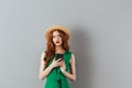 Portrait of thoughtful ginger woman wearing straw hat and green