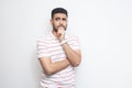 Portrait of thoughtful handsome bearded young man in striped t-shirt standing, looking away and thinking what to do Royalty Free Stock Photo