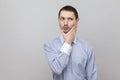 Portrait of thoughtful handsome bristle businessman in classic light blue shirt standing, touching his chin and looking away and Royalty Free Stock Photo