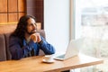 Portrait of thoughtful handsome young adult man freelancer in casual style sitting in cafe with laptop, looking at window and Royalty Free Stock Photo